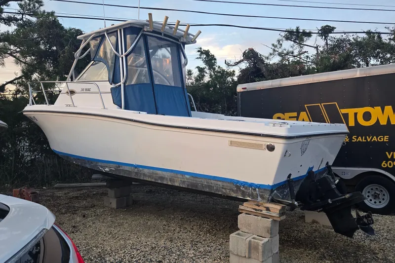 The Image of 1998 Baha Cruisers 240 WAC boat on blocks, parked near a trailer. - 0