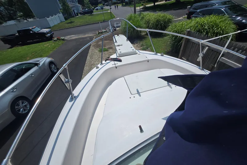 Slide: The Image of 1994 Grady-White Adventure 208 boat parked in a residential driveway, surrounded by cars and greenery. - 16