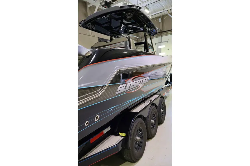 Slide: The Image of 2025 Sunsation 32 CCX boat with sleek design and triple-axle trailer in a showroom. - 10