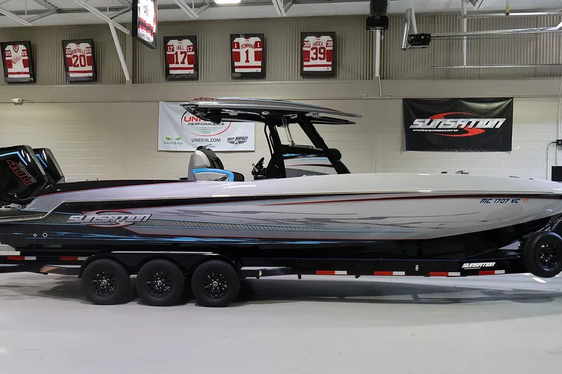 The Image of 2025 Sunsation 32 CCX powerboat on trailer in showroom, featuring sleek design and modern graphics. - 0