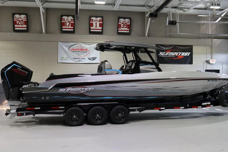 Slide: The Image of 2025 Sunsation 32 CCX boat on trailer in showroom, featuring sleek design and powerful engine. - 2