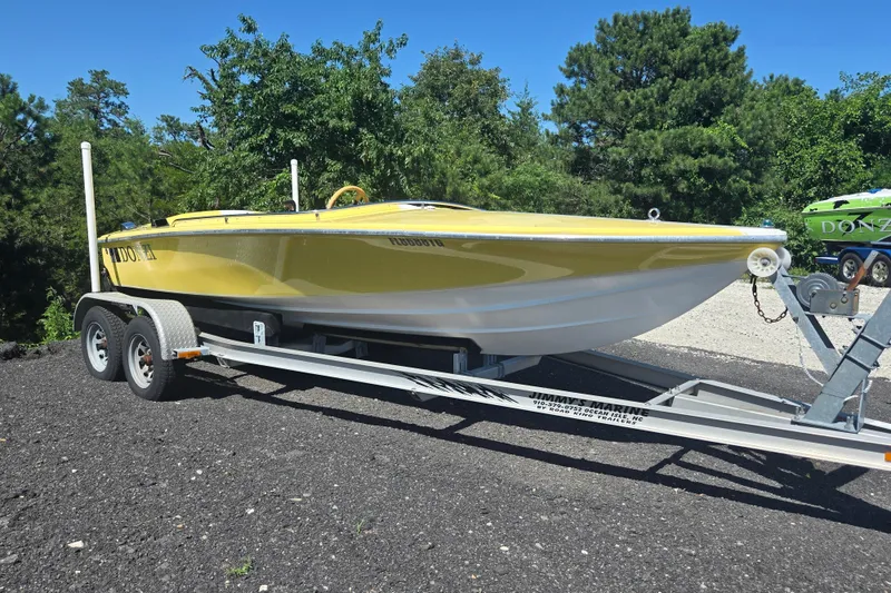 The Image of 1994 Donzi 18 Classic boat in yellow on a trailer, surrounded by greenery. - 0