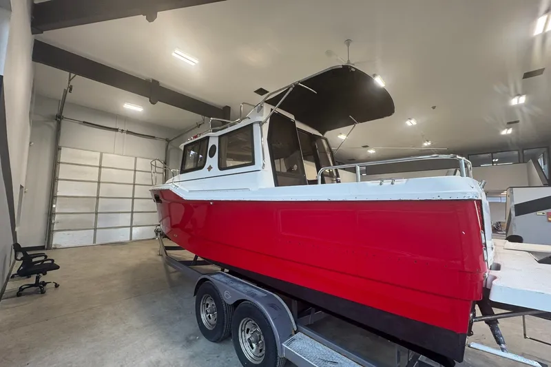 Slide: The Image of 2018 Ranger Tugs R-23 boat with red hull in indoor storage on trailer. - 2
