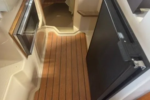 Slide: The Image of 2018 Ranger Tugs R-23 interior with wood flooring and compact kitchen appliances. - 15