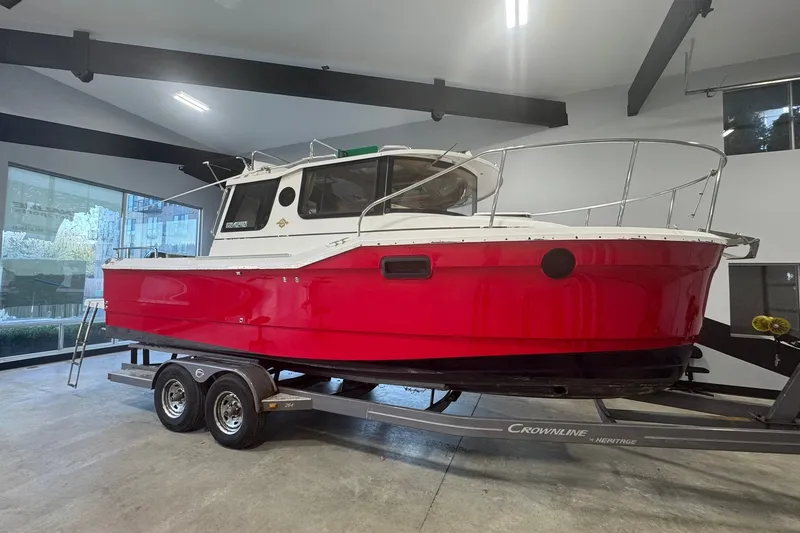 The Image of 2018 Ranger Tugs R-23 boat with red hull on trailer in showroom. - 0