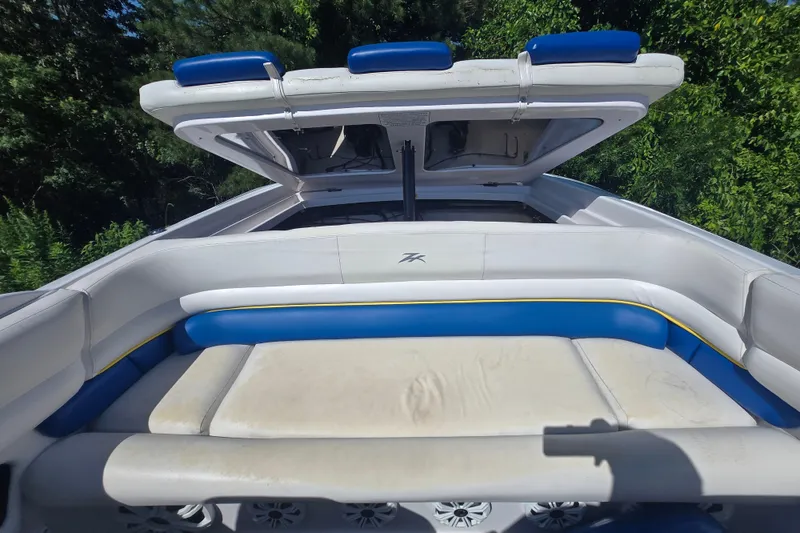 Slide: The Image of 1998 Donzi 28 ZX boat interior with blue and white seating, open hatch, and lush greenery background. - 23
