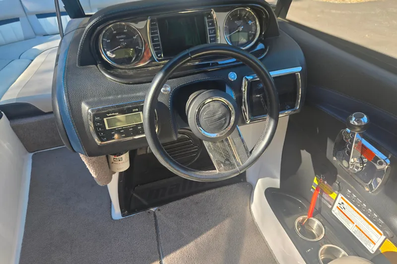 Slide: The Image of Interior dashboard of a 2013 Malibu Wakesetter 24 MXZ boat, featuring steering wheel and controls. - 12
