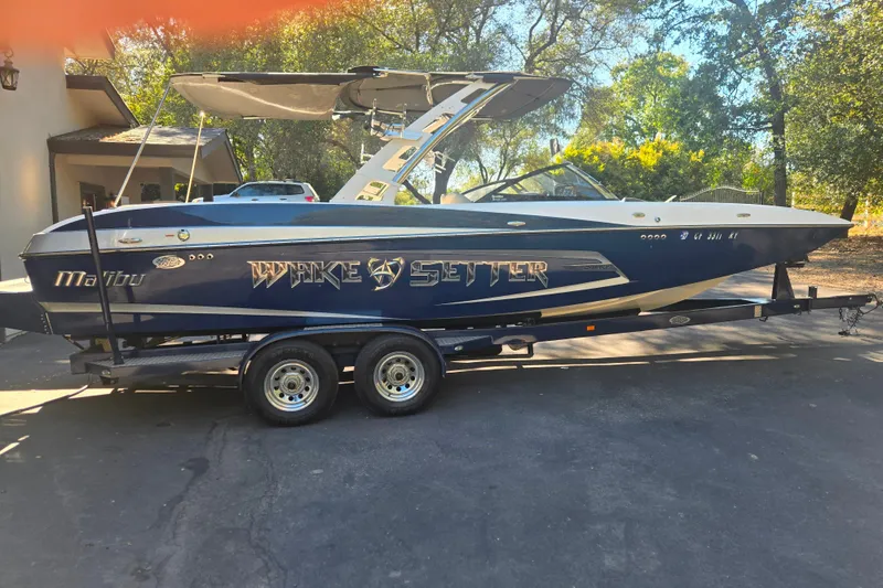 The Image of 2013 Malibu Wakesetter 24 MXZ boat on trailer, parked outdoors. - 1