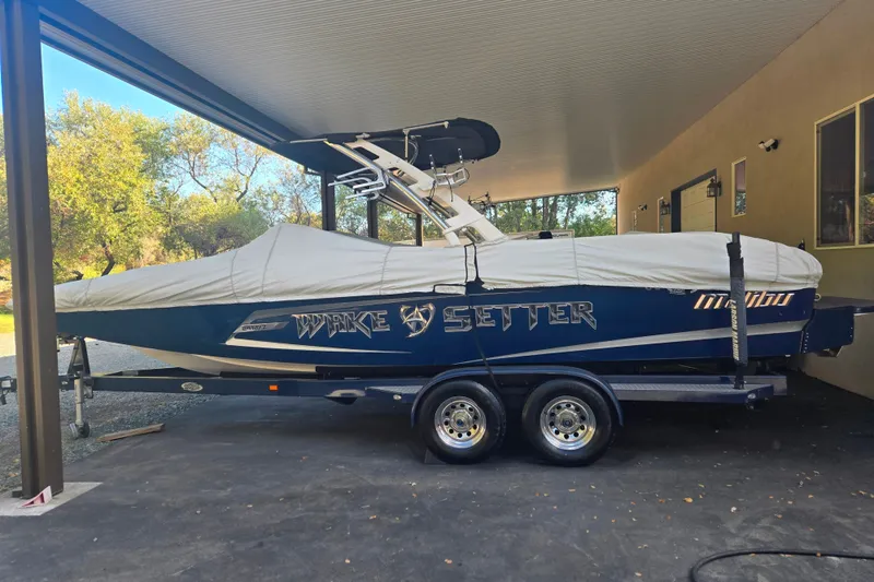 Slide: The Image of 2013 Malibu Wakesetter 24 MXZ boat covered and parked under a shelter. - 25