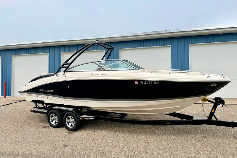 The Image of 2012 Bryant 268 boat on trailer, parked near blue storage units. - 0