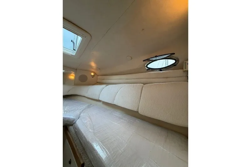 Slide: The Image of Interior cabin of 2001 Sea Ray Sundancer 260 with cozy bedding and porthole window. - 4