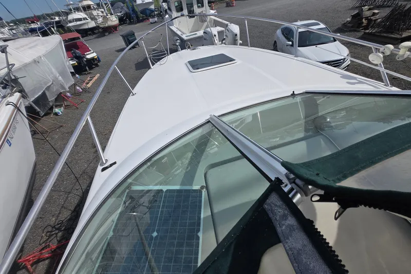 Slide: The Image of 2001 Sea Ray Sundancer 260 boat on dry dock, surrounded by other vessels and vehicles. - 14