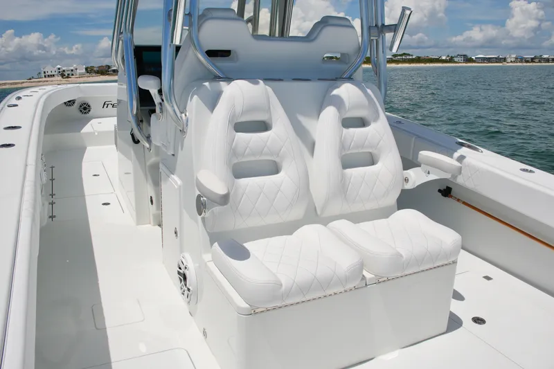 Slide: The Image of 2018 Freeman 34VH boat with luxurious white seating, docked near a scenic shoreline. - 54