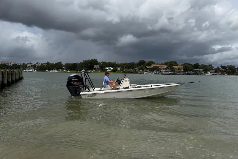 Slide: The Image of 2020 Hewes Redfisher 18 boat on water under cloudy sky, near shoreline. - 7