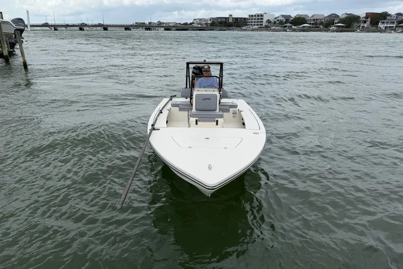 Slide: The Image of 2020 Hewes Redfisher 18 boat on water, with person steering near coastal area. - 6