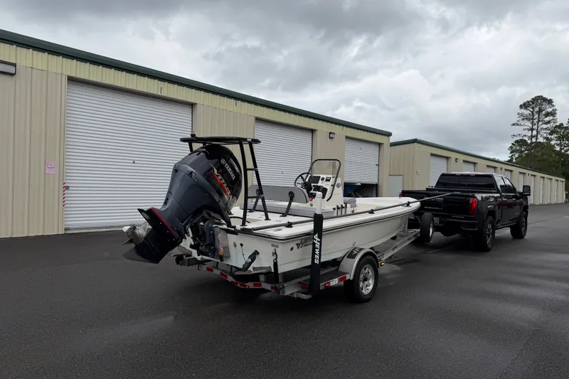 Slide: The Image of 2020 Hewes Redfisher 18 boat on trailer, parked near storage units, overcast sky. - 14