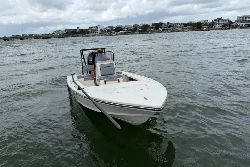 Slide: The Image of 2020 Hewes Redfisher 18 boat on water, with coastal buildings in the background. - 3