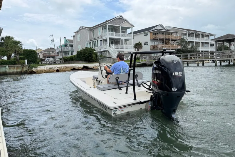 Slide: The Image of 2020 Hewes Redfisher 18 boat navigating coastal waters near waterfront homes. - 2