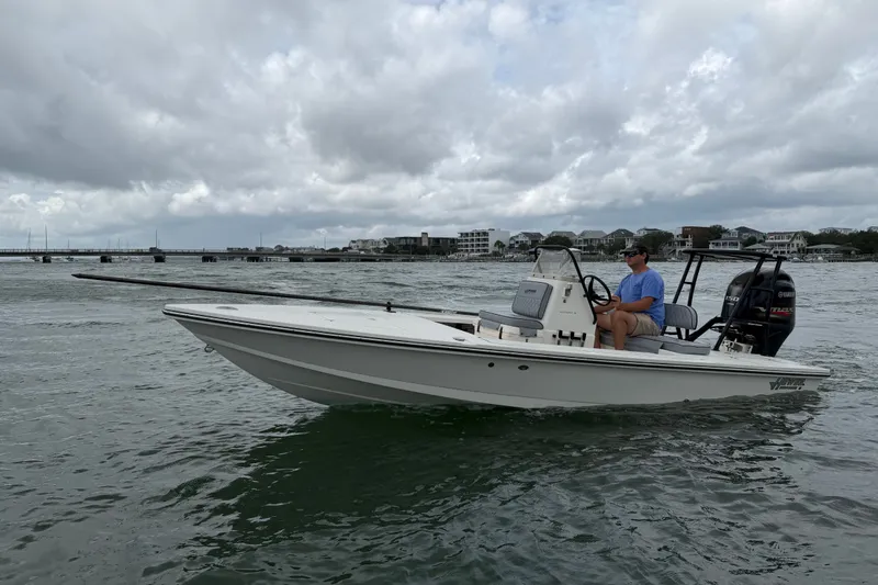 The Image of 2020 Hewes Redfisher 18 boat on water, cloudy sky, person at helm. - 1