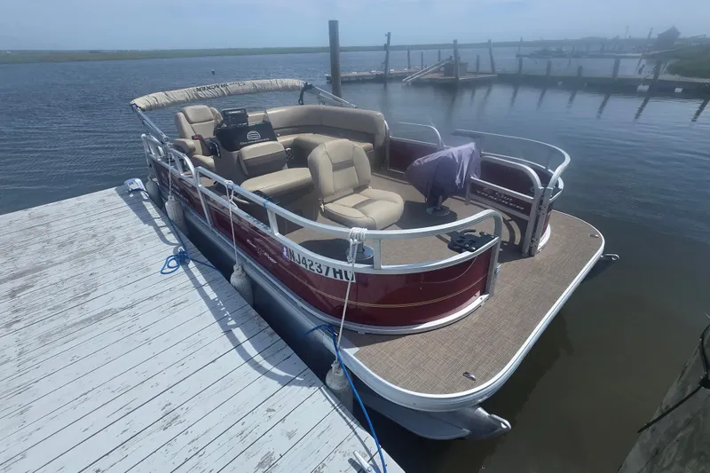 The Image of 2024 Sun Tracker Bass Buggy 16 XL Select pontoon boat docked by the water. - 0