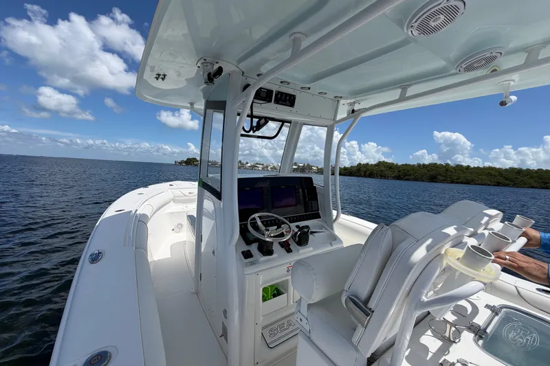 Slide: The Image of 2019 Sea Hunt Gamefish 30 boat interior with helm, seats, and ocean view under blue sky. - 16