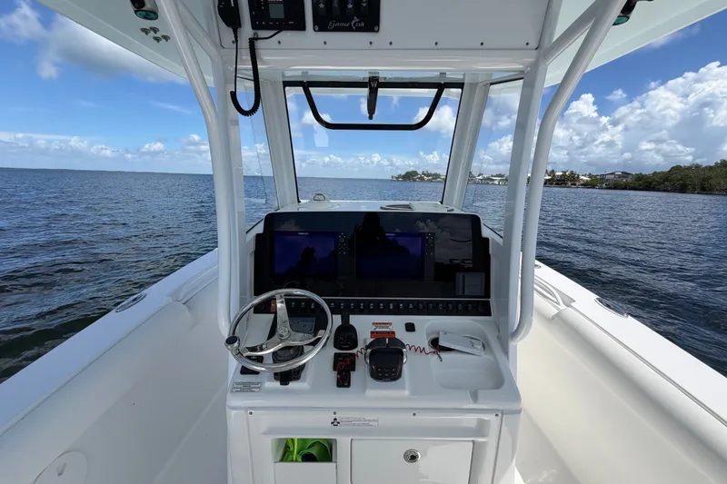 Slide: The Image of 2019 Sea Hunt Gamefish 30 boat console with steering wheel and navigation equipment on open water. - 15
