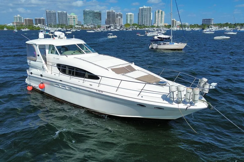 Slide: The Image of 2003 Sea Ray 480 Motor Yacht cruising in a bustling harbor with city skyline backdrop. - 1