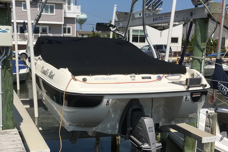 Slide: The Image of 2012 Stingray 195 LS/LX boat docked, covered, with visible outboard motor and marina background. - 4