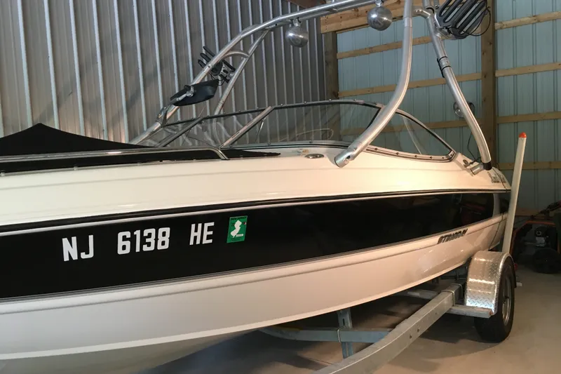 Slide: The Image of 2012 Stingray 195 LS/LX boat in storage, featuring sleek design and trailer. - 1