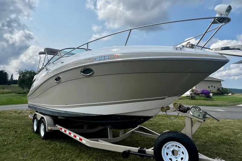 Slide: The Image of 2007 Four Winns 288 Vista boat on trailer, parked on grass under cloudy sky. - 2