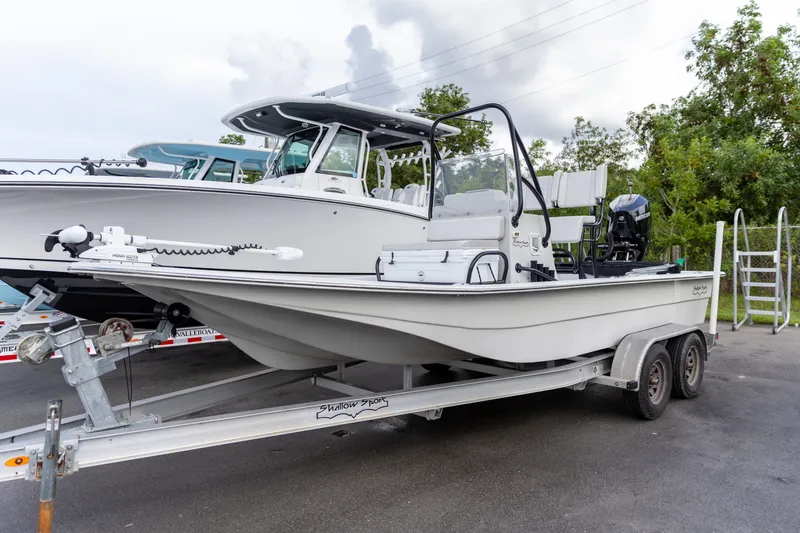 The Image of 2020 Shallow Sport 21 Sport boat on trailer, parked outdoors with trees in background. - 0