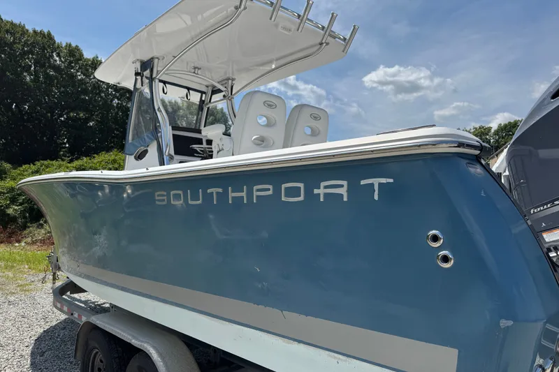 Slide: The Image of 2013 Southport 27 FE boat with blue hull, parked on a trailer under a clear sky. - 45