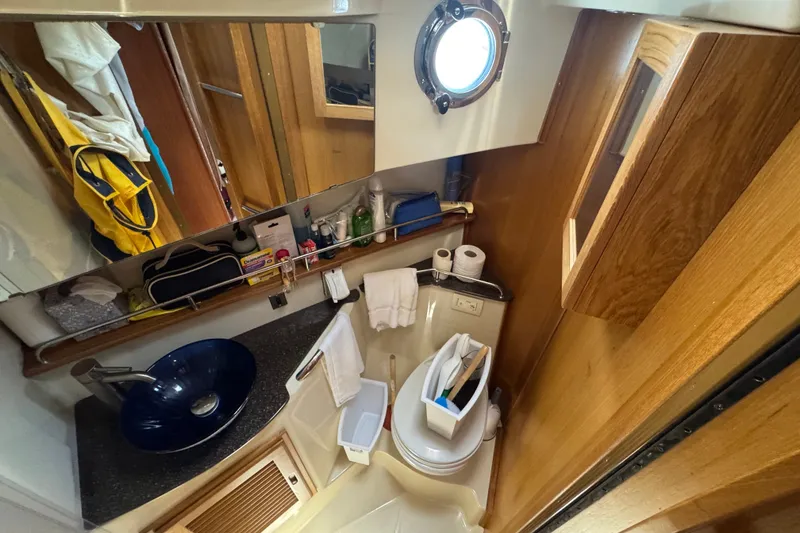 Slide: The Image of 2020 Ranger Tugs R-31 CB bathroom with modern sink, mirror, and wooden cabinetry. - 24