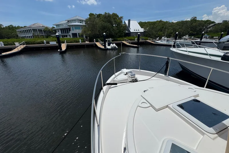 Slide: The Image of 2020 Ranger Tugs R-31 CB docked at a marina with waterfront homes in the background. - 34