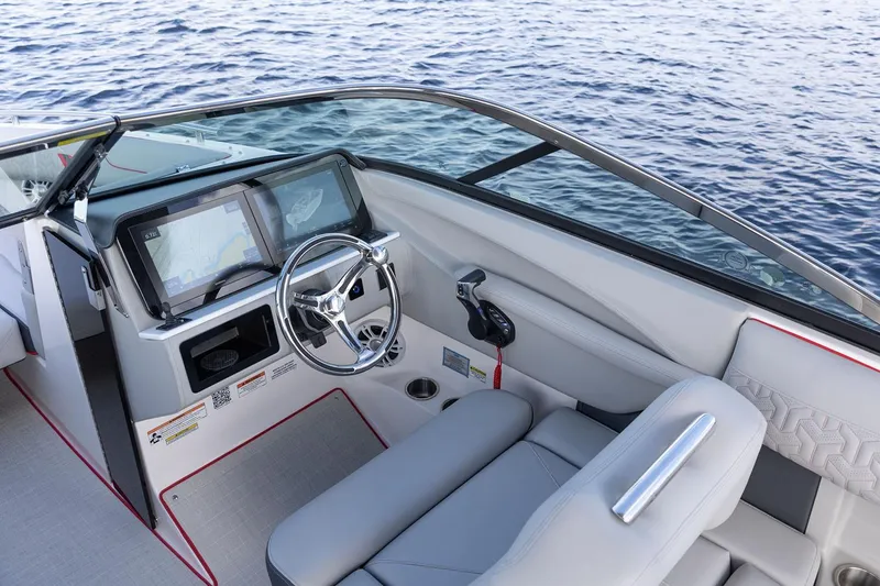 Slide: The Image of Manufacturer Provided Image: 2026 Regal LX6 boat cockpit with modern steering and navigation system on calm water. - 12