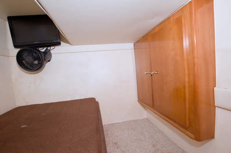 Slide: The Image of 2001 Carver 466 Motor Yacht cabin with TV, fan, and wooden cabinets. - 54