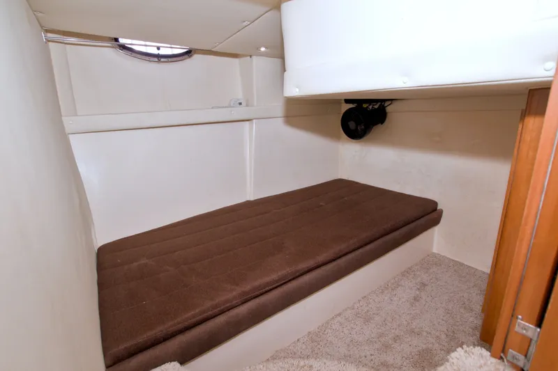 Slide: The Image of 2001 Carver 466 Motor Yacht cabin with brown cushioned bed and circular window. - 52