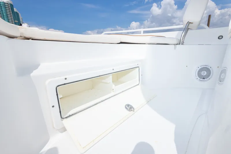 Slide: The Image of 2019 Sea Hunt BX25FS boat interior with open storage compartment under clear blue sky. - 38