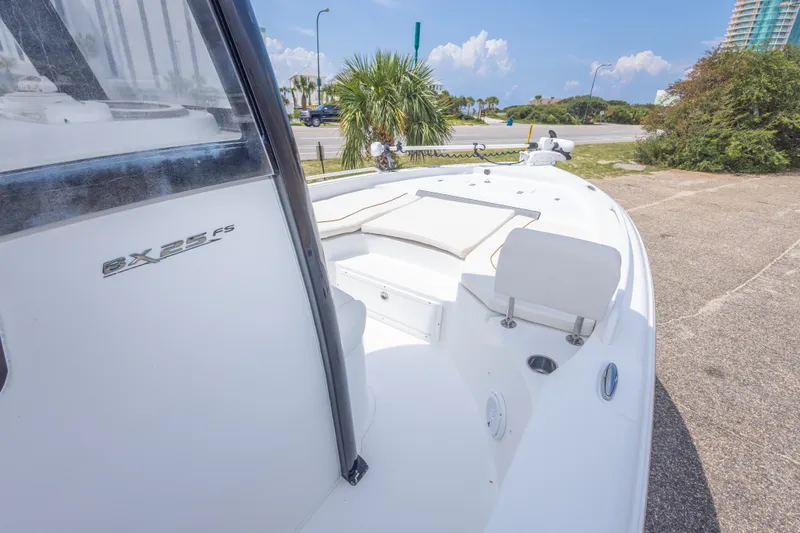 Slide: The Image of 2019 Sea Hunt BX25FS boat with sleek white deck and seating, parked outdoors. - 46