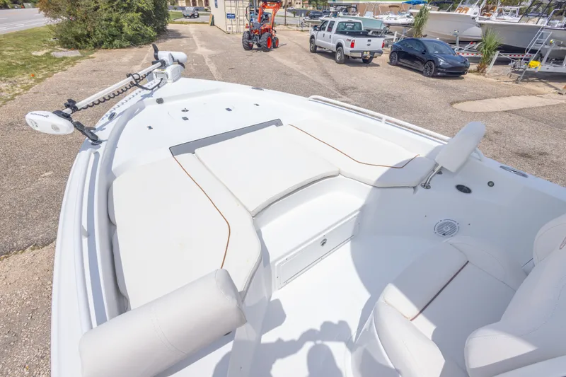 Slide: The Image of 2019 Sea Hunt BX25FS boat interior with seating and trolling motor, parked outdoors. - 24