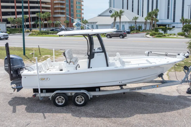 Slide: The Image of 2019 Sea Hunt BX25FS boat on trailer, parked near road with buildings in background. - 12