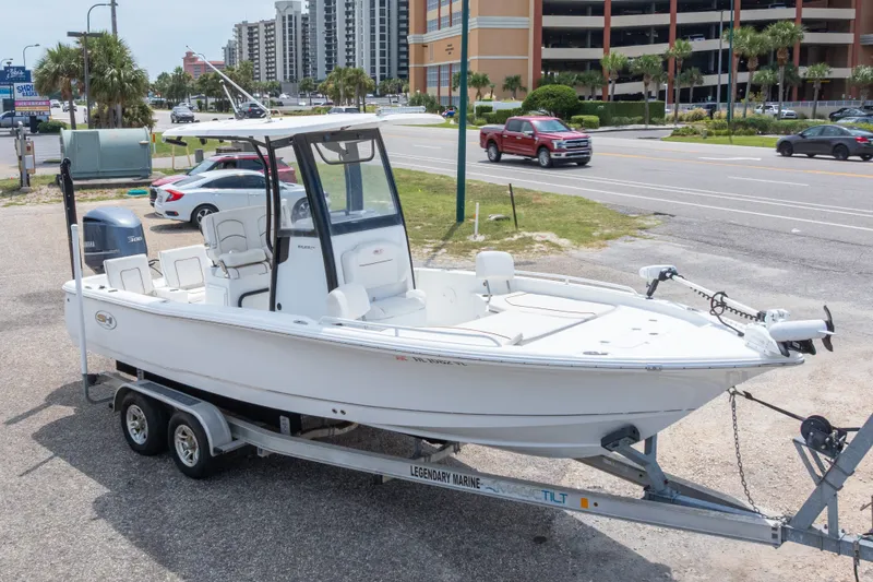 Slide: The Image of 2019 Sea Hunt BX25FS boat on trailer, parked near a busy street. - 1