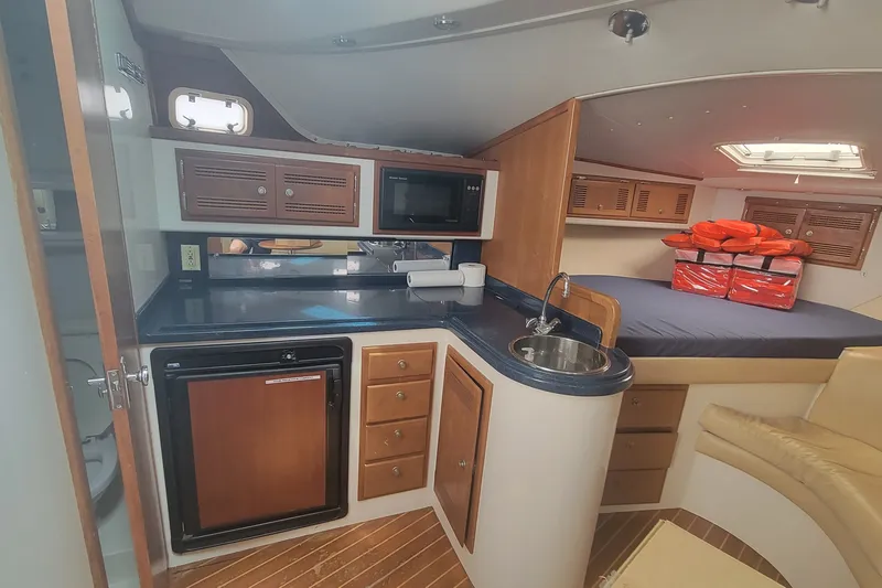 Slide: The Image of Interior of a 1995 Cabo 35 Express boat featuring a compact kitchen and cozy sleeping area. - 10