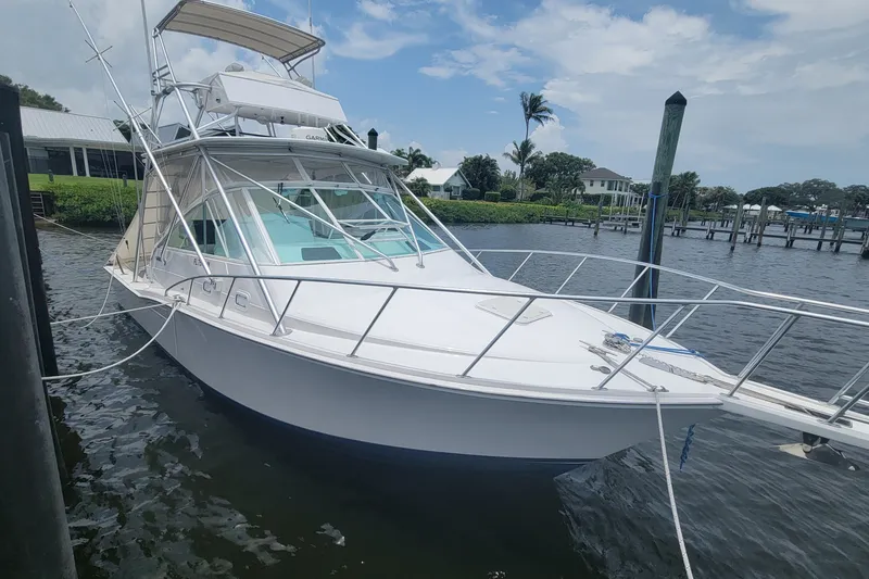 The Image of 1995 Cabo 35 Express boat docked by the waterfront under a partly cloudy sky. - 1