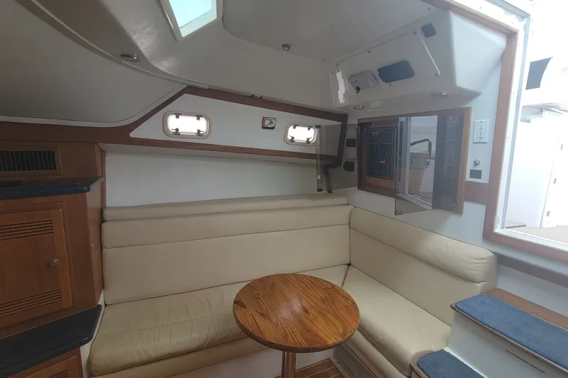 Slide: The Image of Interior of a 1995 Cabo 35 Express yacht with beige seating and wooden table. - 11