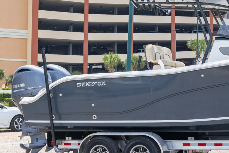 Slide: The Image of 2016 Sea Fox 266 Commander boat on trailer, featuring Yamaha engines, parked near a multi-level garage. - 9