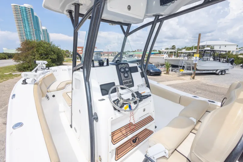 Slide: The Image of 2016 Sea Fox 266 Commander boat interior with steering console and seating, docked near buildings. - 46