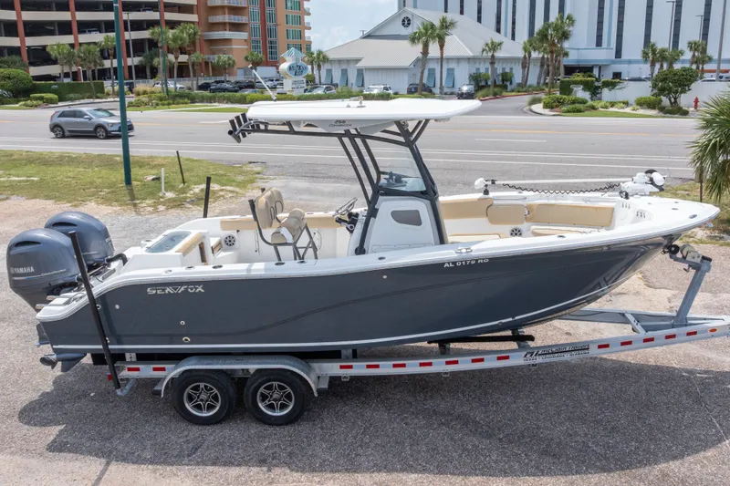 Slide: The Image of 2016 Sea Fox 266 Commander boat on trailer, parked near road with buildings in background. - 1
