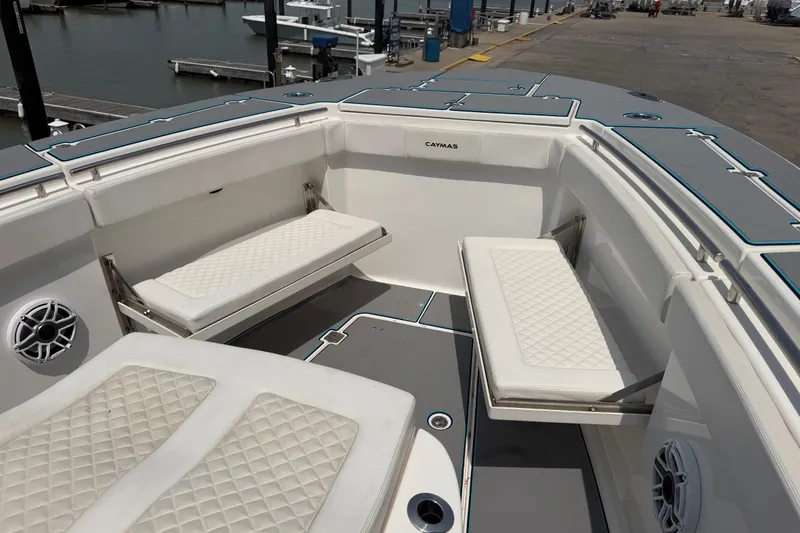 Slide: The Image of 2021 Caymas 341 CC boat interior with cushioned seating and speakers at a marina. - 28