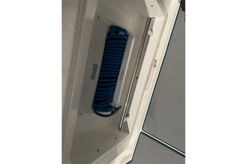 Slide: The Image of Coiled blue hose in Caymas 341 CC boat, 2021 model, stored in compartment. - 44